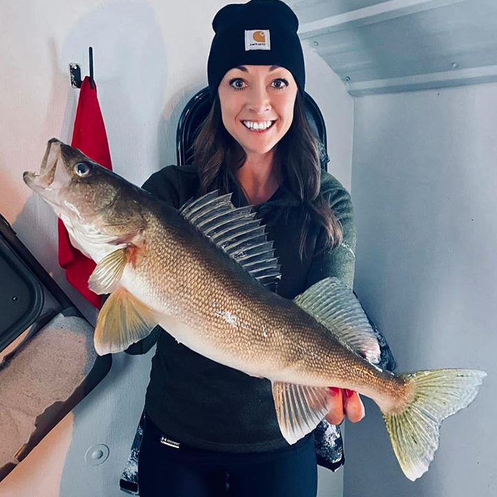 image of ice fishing woman holding large walleye caught on Lake of the woods