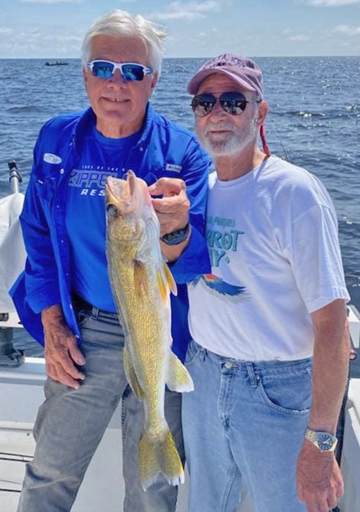 image of Nick Panovich holding walleye for fishing customer on charter boat