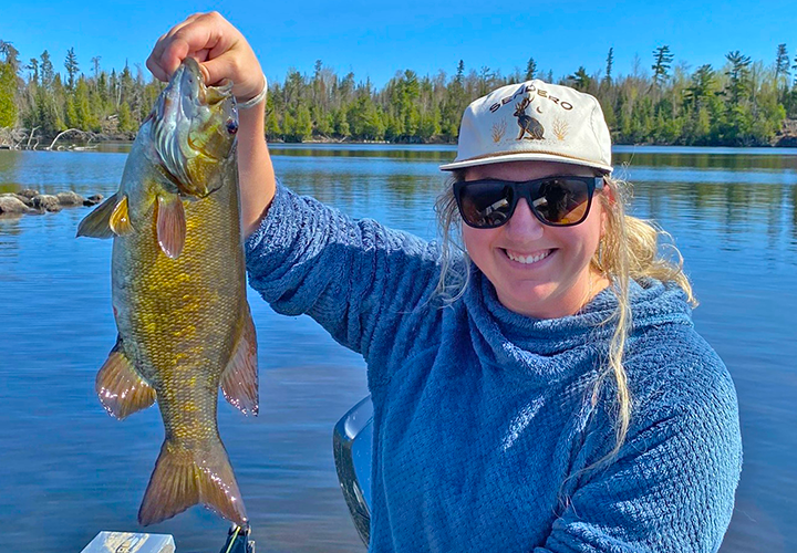 image of young woman holding large smallmouth bass caught near Ely MN 