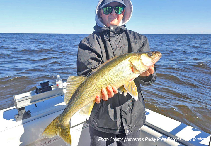 image of young man holding large walleye he caught while on a charter fishing trip to Lake of the Woods 