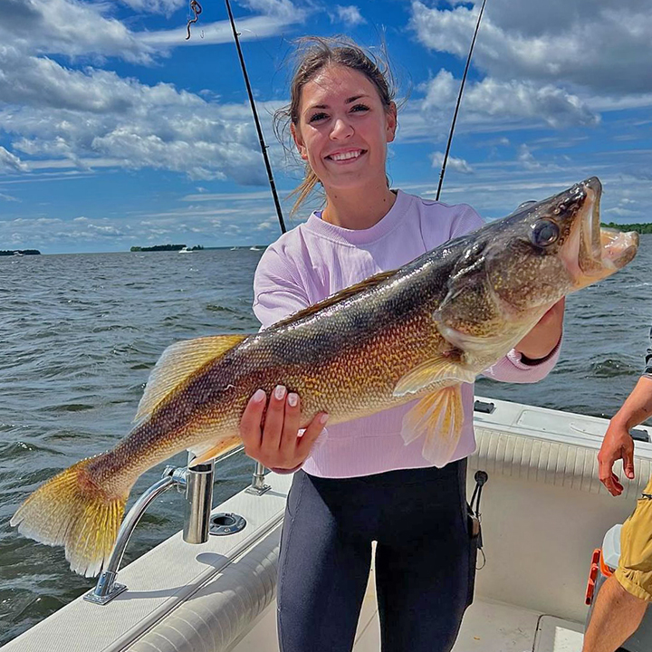 image of woman holding giant walleye she caught on the Border View Lodge fishing charter
