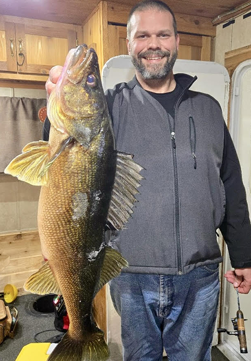 image of ice fisherman holding huge walleye he caught ice fishing near ely minnesota