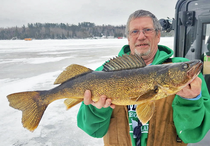image of ice fisherman holding big walleye he caught in the Ely Minnesota region