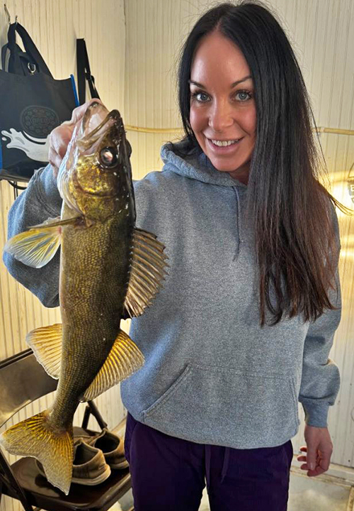 image of woman holding big walleye she caught ice fishing 