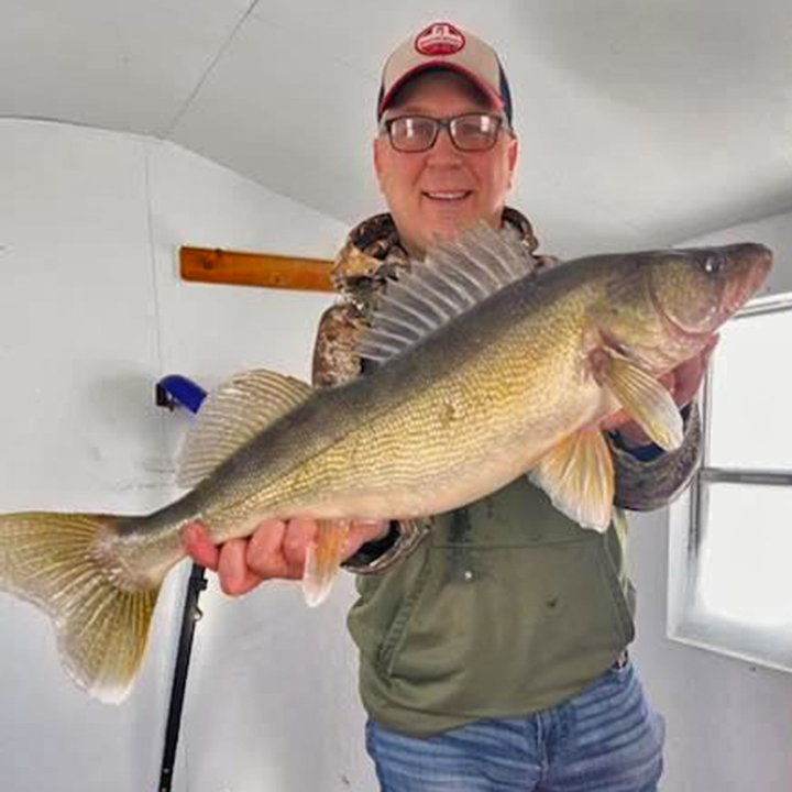 image of ice fisherman holding big walleye caught on Lake of the Woods 