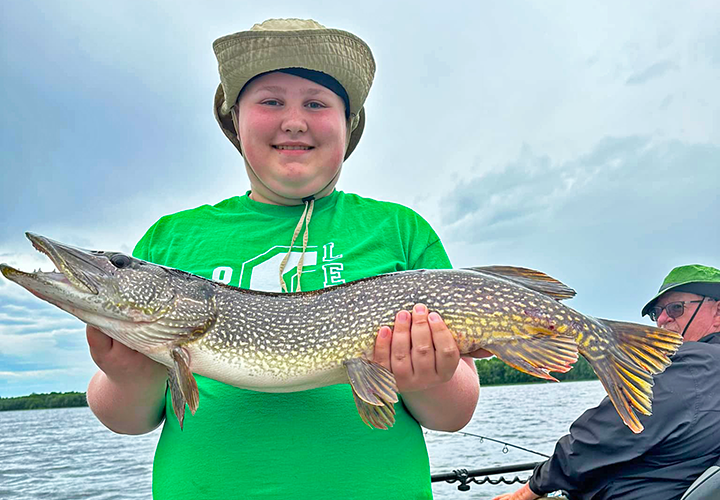 image of Bryce Demuth holding big northern pike he caught in the Grand Rapids area