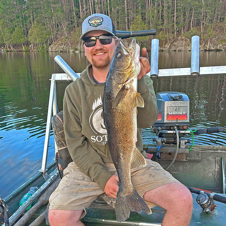 image of young man holding big walleye he caught near Ely Minnesota 